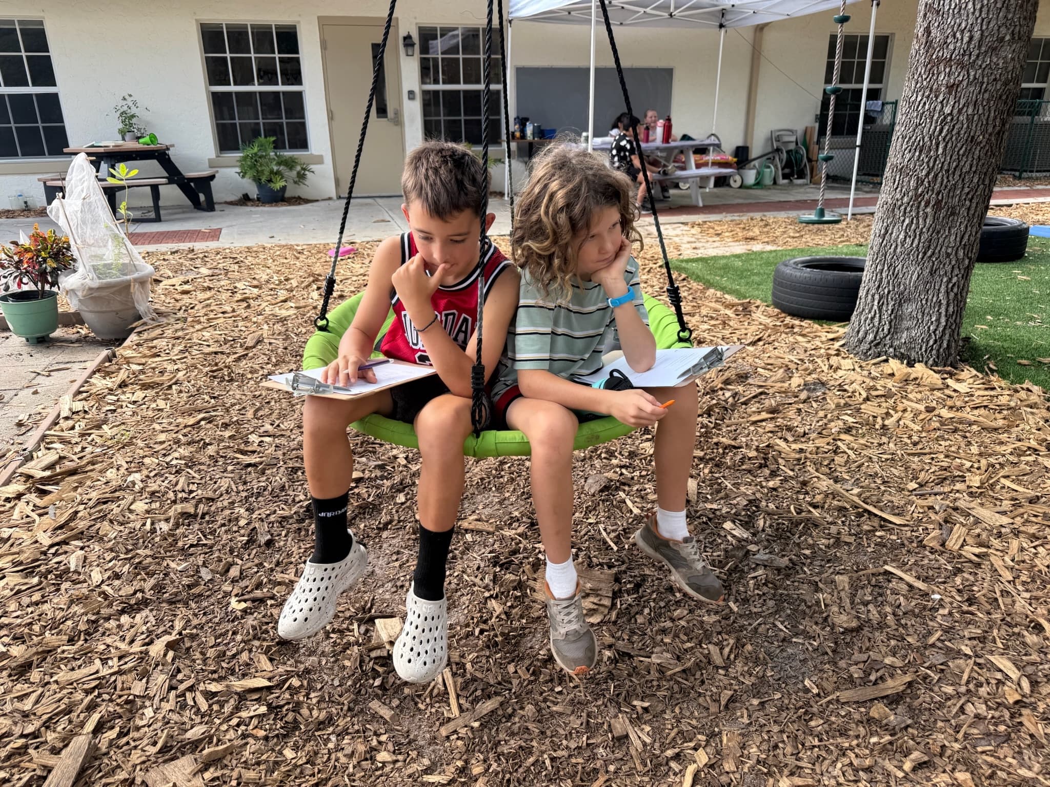 Two students reading together on the outdoor swing at The Grow Co-op